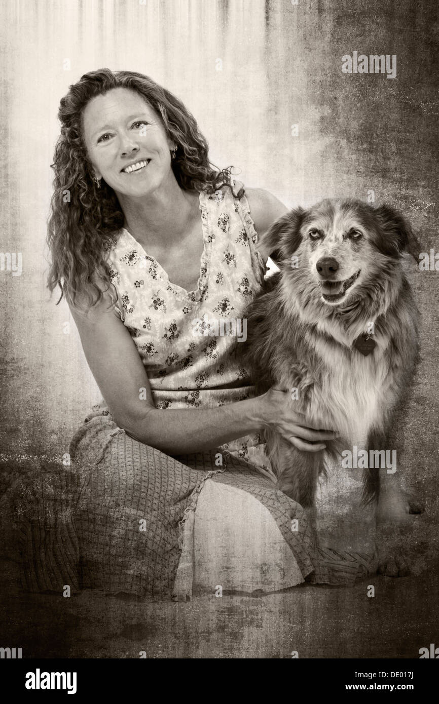 Black & white studio photograph of attractive woman in summer dress with her pet dog, Miss Kitty, an Australian Shepherd mix Stock Photo