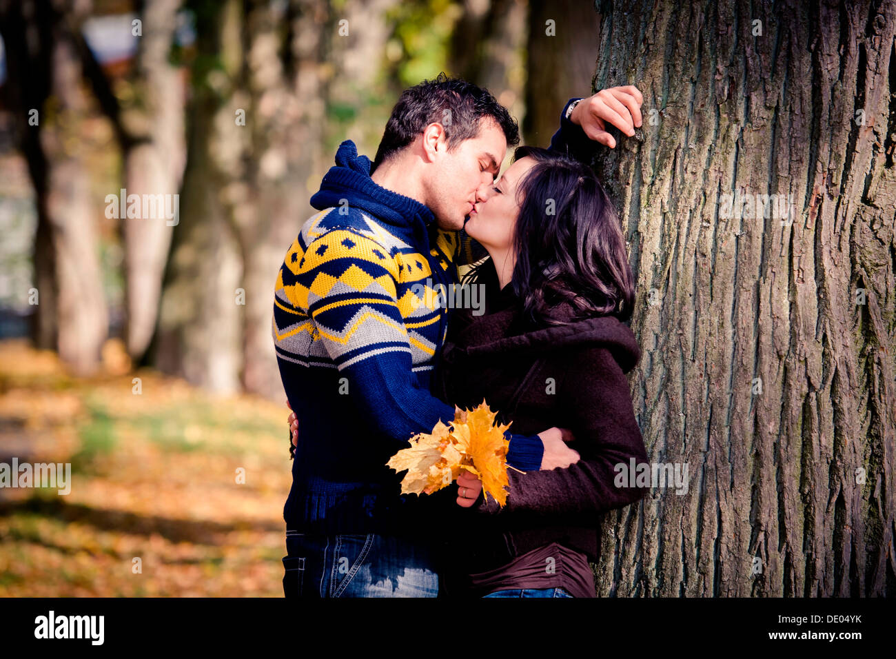 Couple kissing against tree hi-res stock photography and images - Alamy