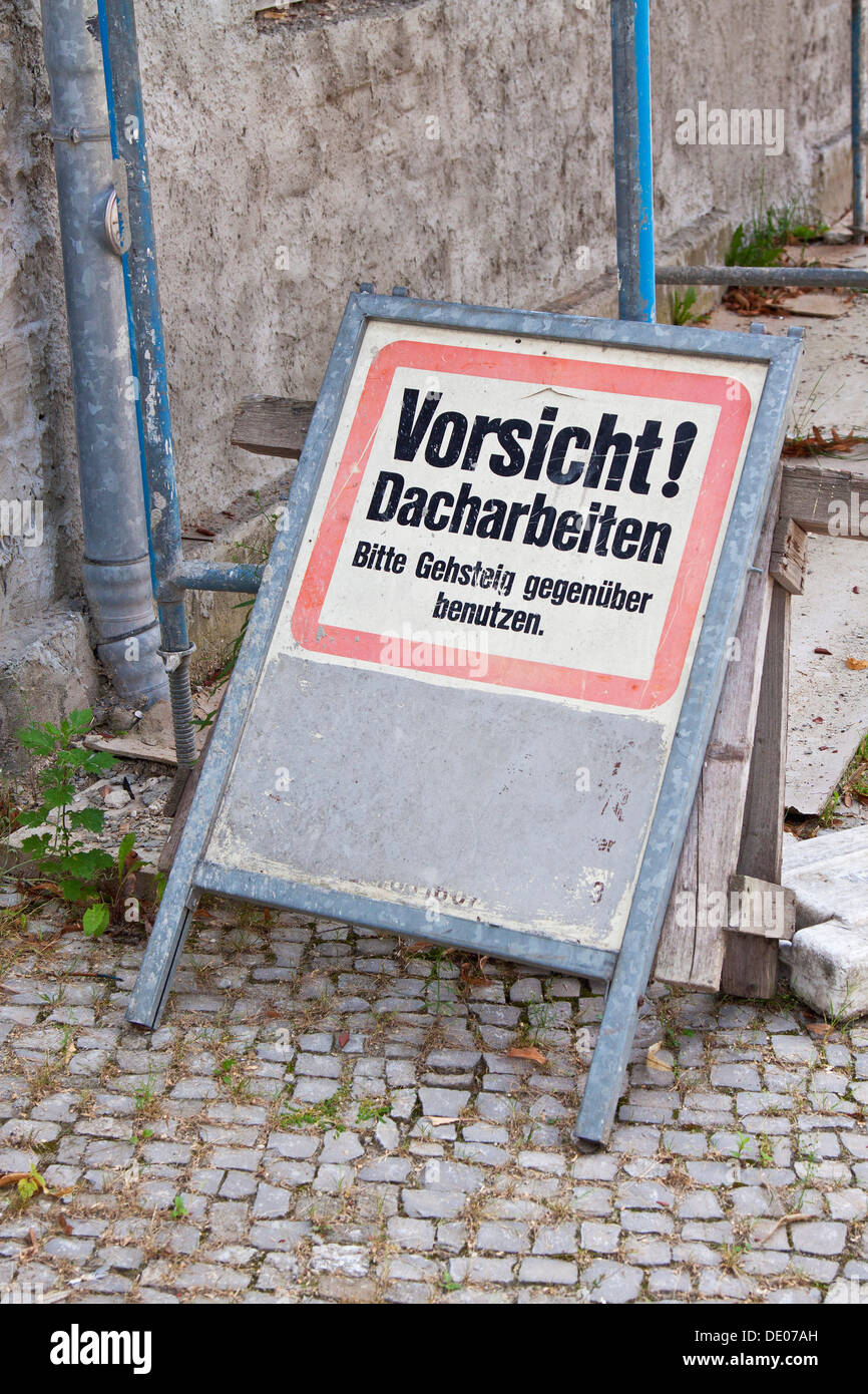Sign on scaffolding, Vorsicht! Dacharbeiten, Bitte Gehsteig gegenueber benutzen, German for Caution! Roofing work Stock Photo