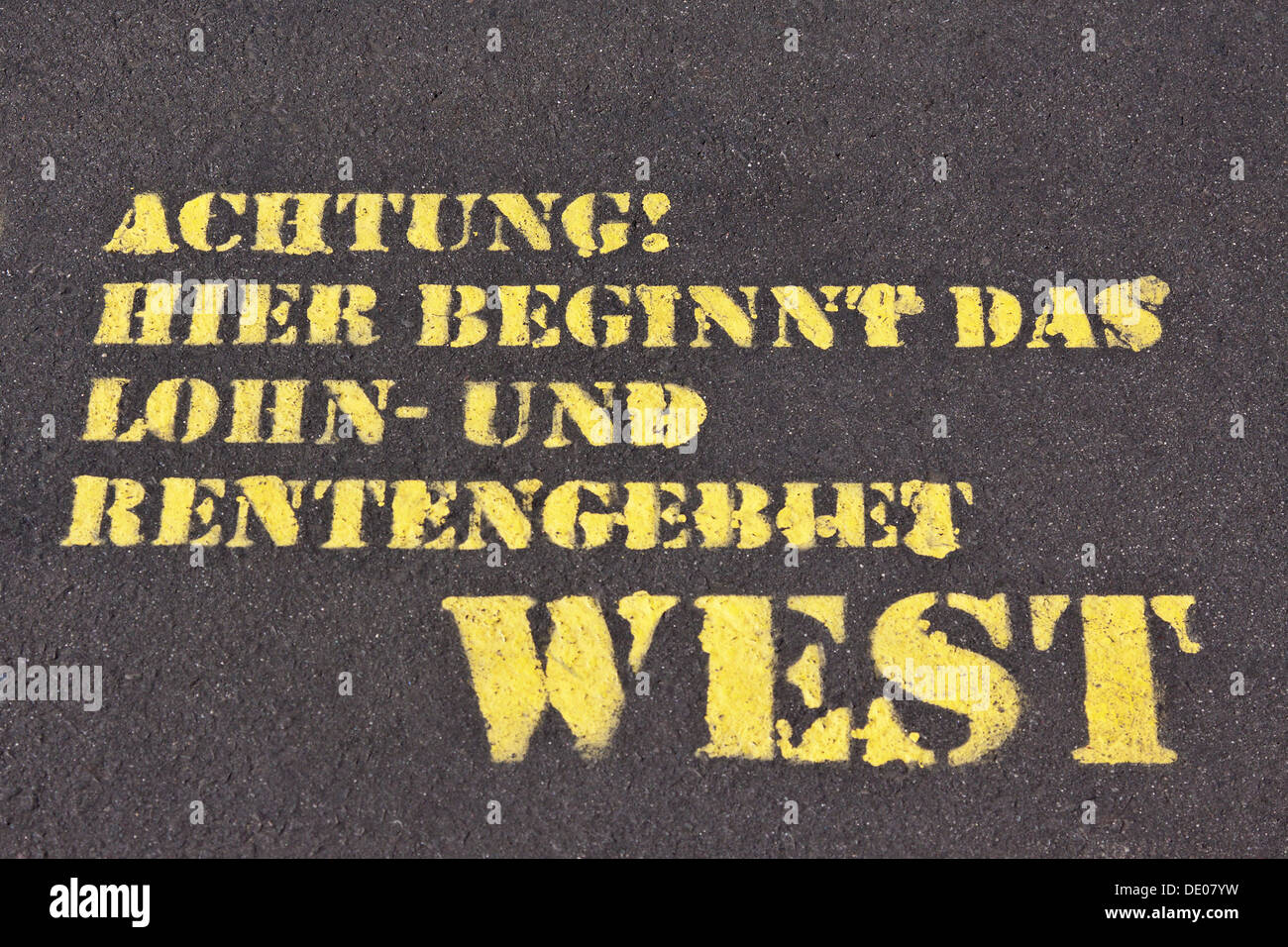 Sprayed words 'Achtung! Hier beginnt das Lohn- und Rentengebiet West' or 'Warning! Here begins the wage and pension area west' Stock Photo