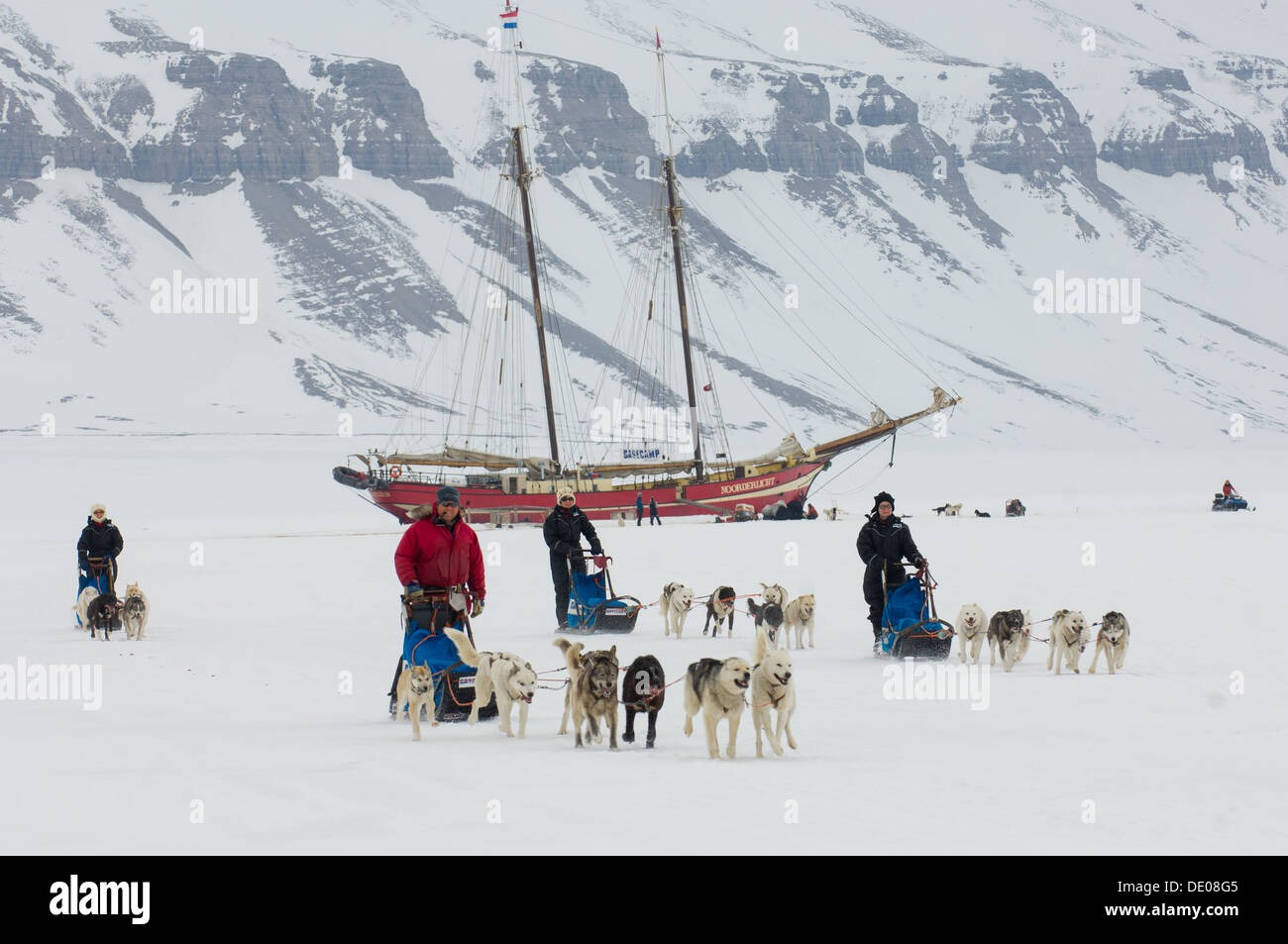 Dog sled teams racing away from the Noorderlicht 'Ship in the Ice', Temple Fjord (Tempelfjorden), Spitsbergen, Svalbard Archipelago, Norway Stock Photo