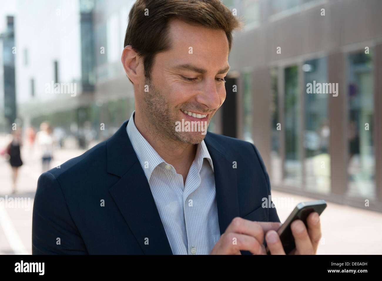 Businessman using smartphone outdoors Stock Photo