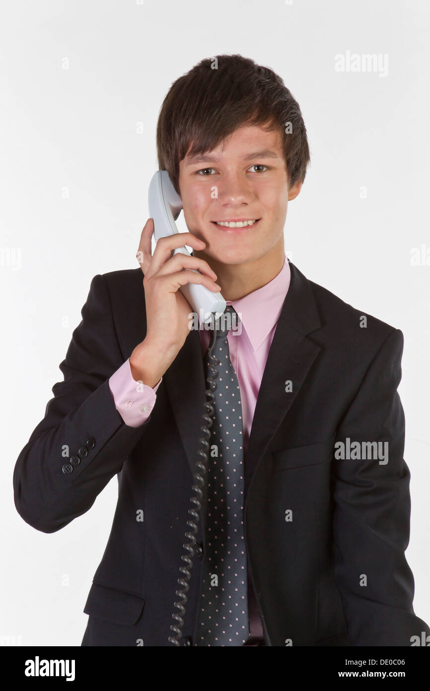 Young man wearing a suit and tie, smiling while talking on the phone Stock Photo