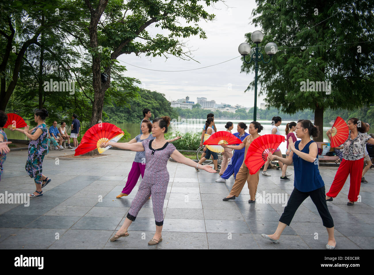 Vietnamese ladies gymnastics with traditional fan in Hoan Kiem lake side at the morning in Hanoi, Vietnam Stock Photo