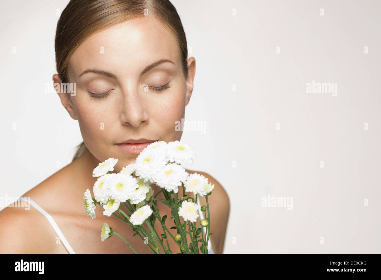 Young woman enjoying fragrence of bouquet of daisies Stock Photo