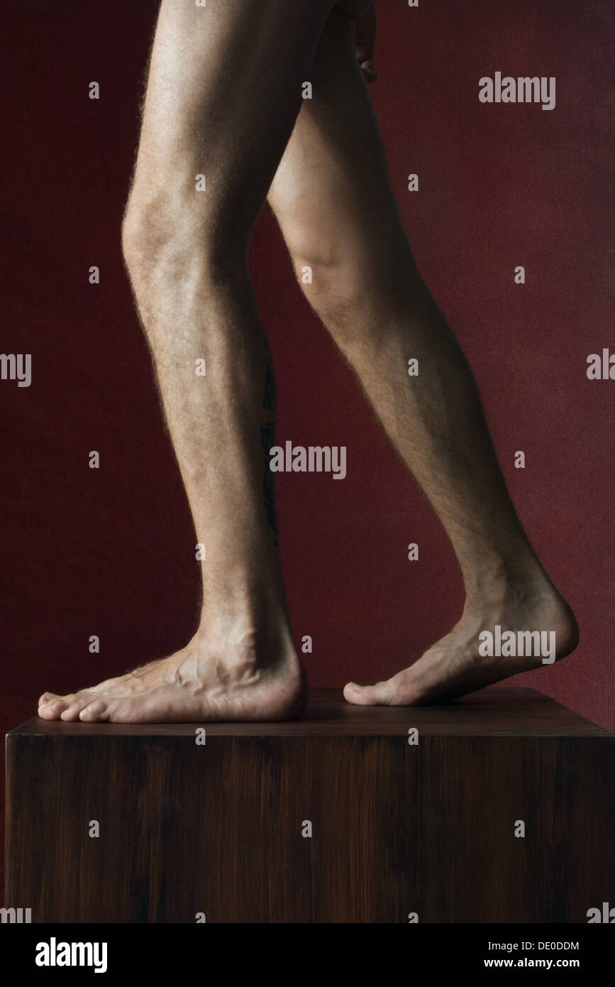 Man's bare legs on pedestal, side view Stock Photo