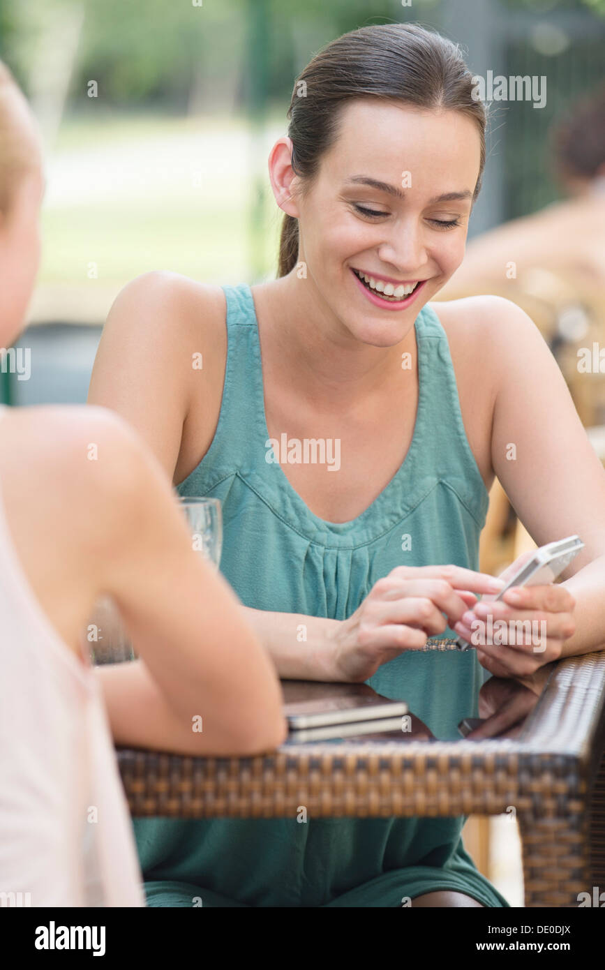 Women chatting outdoors, one woman looking at smartphone Stock Photo