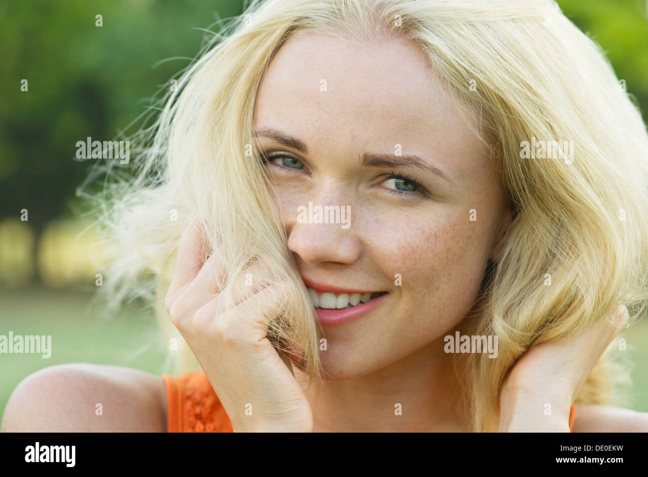 Young woman with hands in hair, smiling, portrait Stock Photo