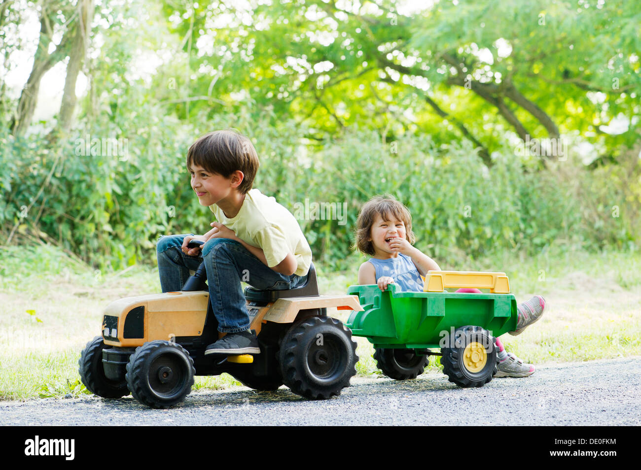 Young brother and sister riding on toy tractor Stock Photo - Alamy