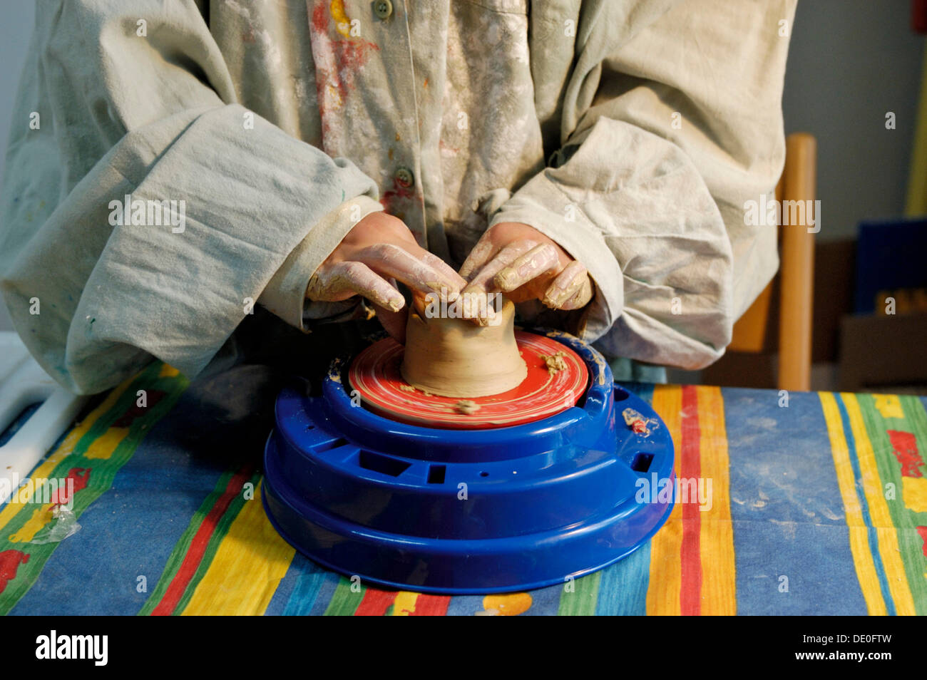 Children's hands making pottery, turning a jar from clay on a potter's