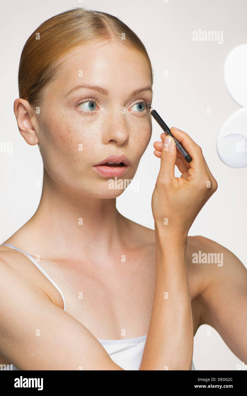 Young woman applying eyeliner Stock Photo