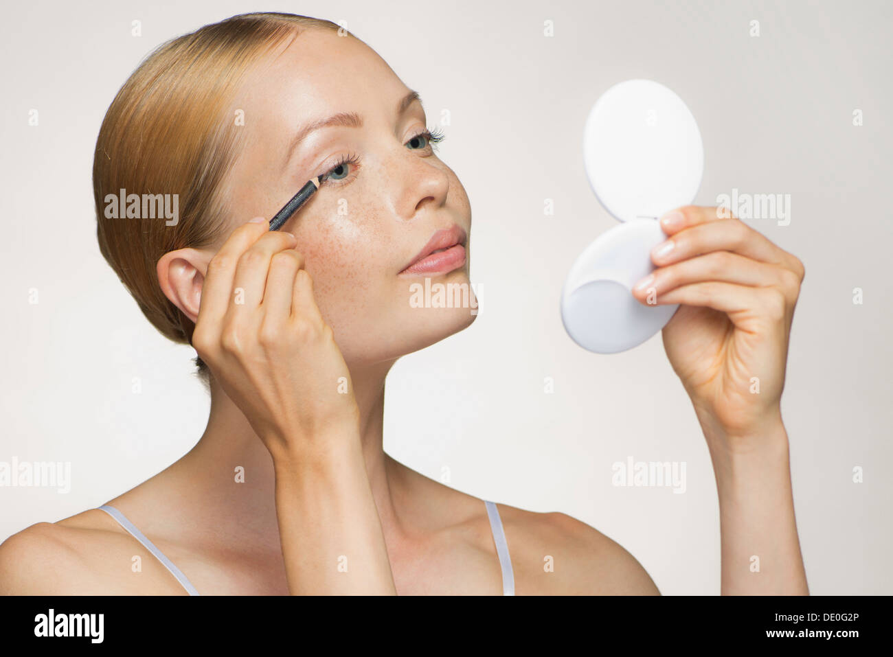 Young woman applying eyeliner Stock Photo