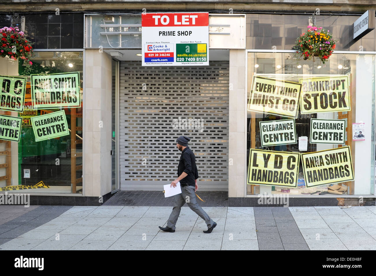 A job hunter with a cv in hand walks passed a closed down shop on Queens Street in Cardiff - Cardiff's main shopping street. Stock Photo
