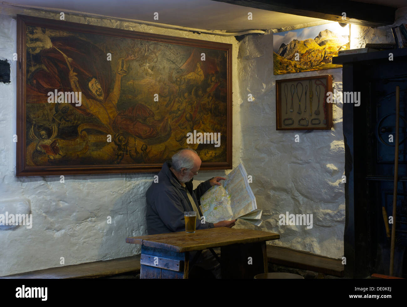 Elderly man reading Ordnance Survey map in climber's bar of the Old Dungeon Ghyll Hotel, Langdale, Lake District, Cumbria UK Stock Photo