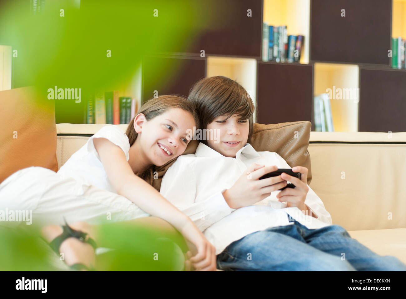 Brother and sister looking at cell phone together Stock Photo