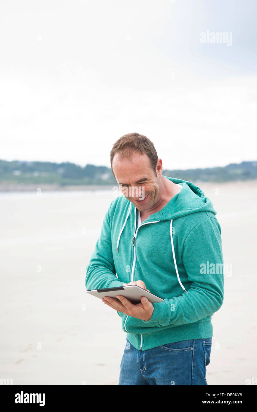 Man playing with an iPad on a beach Stock Photo