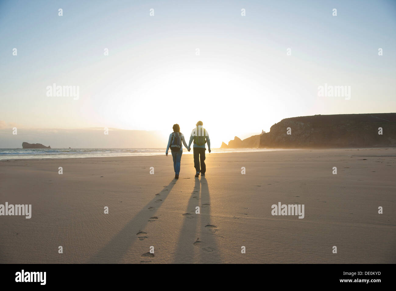 Couple walking hand in hand along beach at sunset hi-res stock ...
