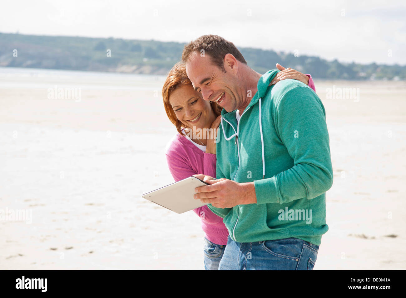 Couple playing with an iPad on a beach Stock Photo