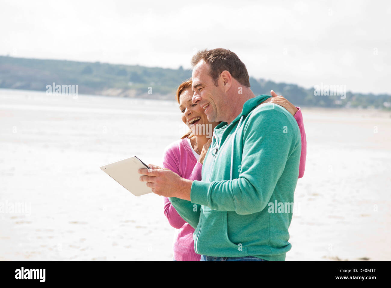 Couple playing with an iPad on a beach Stock Photo