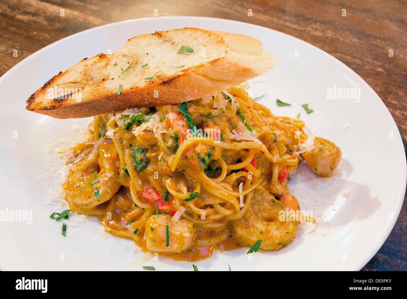 Seafood Spaghetti Pasta Cooked in Tomato Cream Sauce with Prawns Scallops White Fish Basil Bell Peppers and Bread Stock Photo