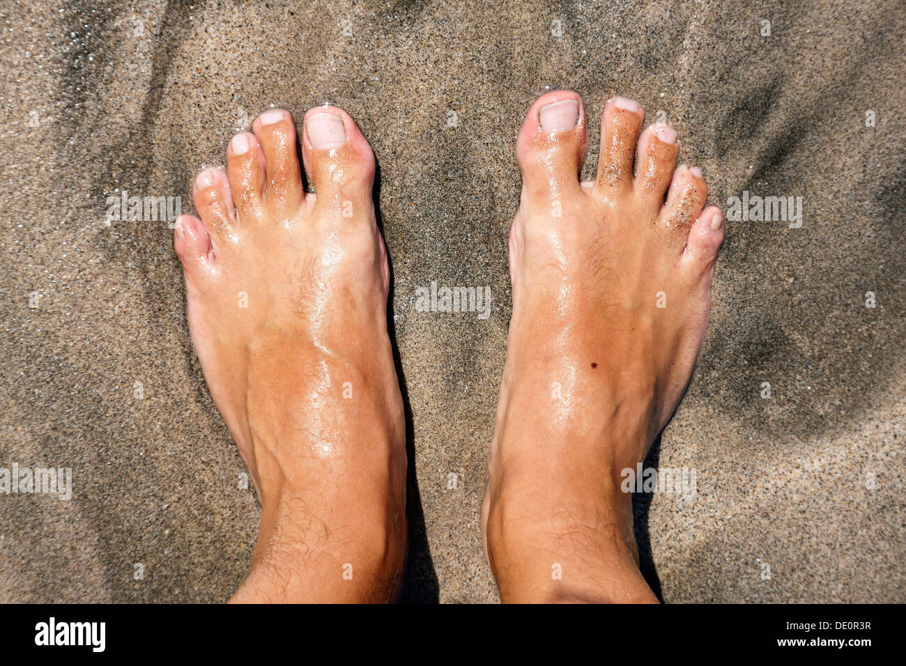 Feet on a beach, being lapped by the sea Stock Photo