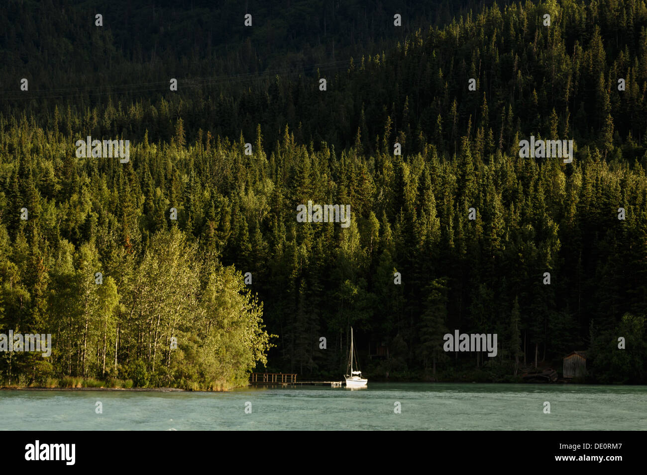 Sailboat at dock in a mountain forest lake near a cabin in the