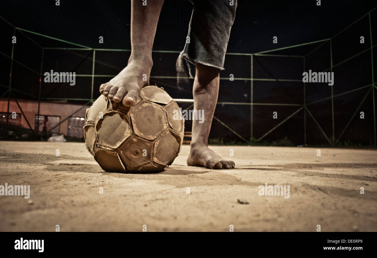 Soccer in Brazil Poor dark-skinned shoeless boy plays soccer in Complexo do Alemao a group of favelas in northern Rio de Janeiro Stock Photo