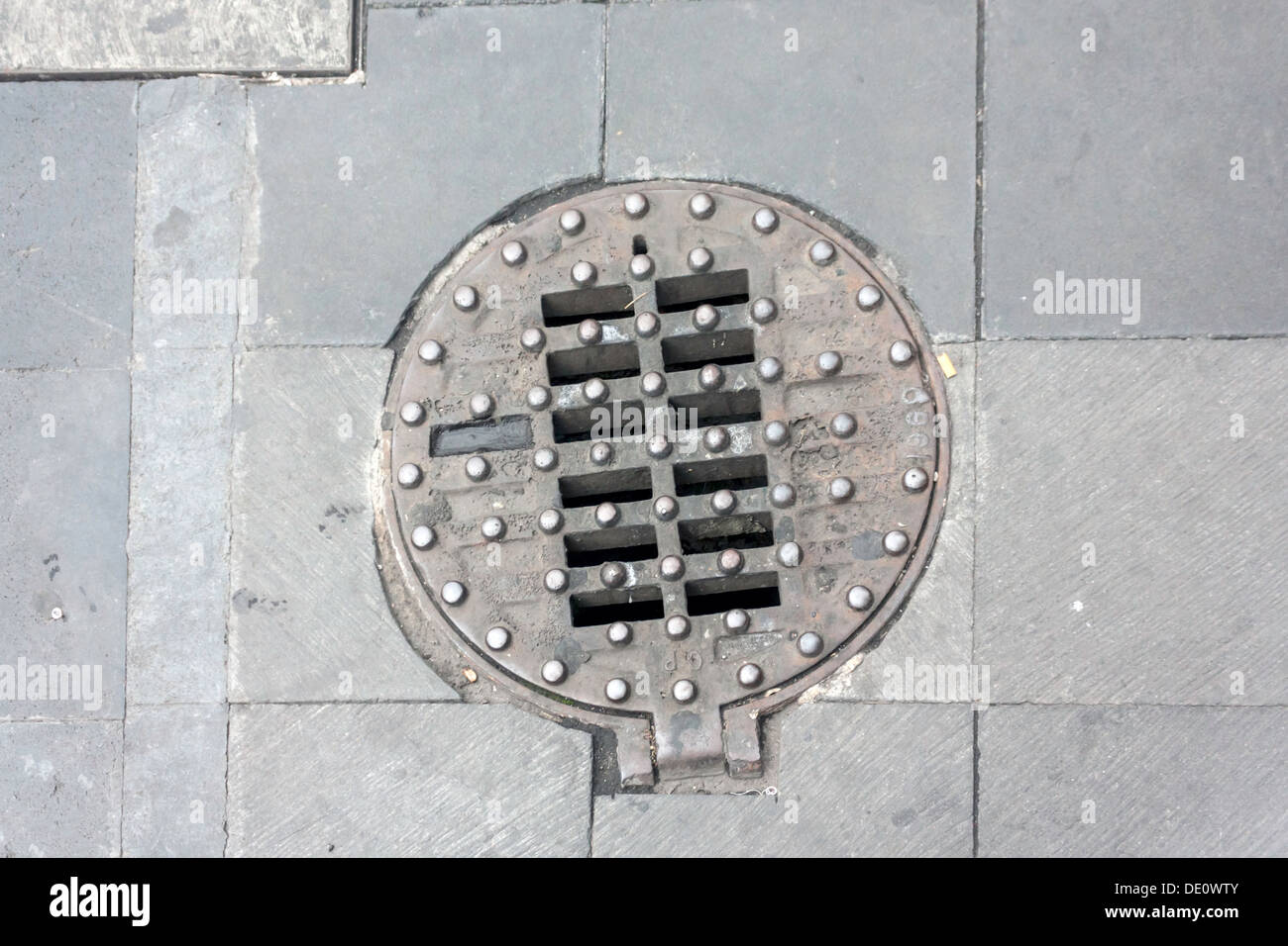 Hinged and studded, cast iron manhole cover in the old historic district of Mexico City, Mexico. Stock Photo