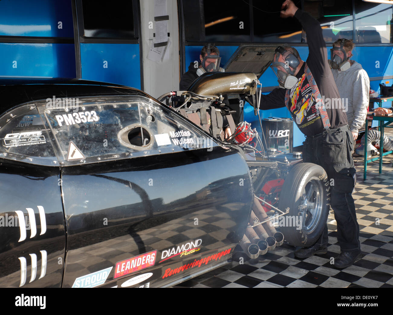 Mechanics preparing their Pontiac Firebird Pro Mod for drag racing at Santa Pod pits. Stock Photo