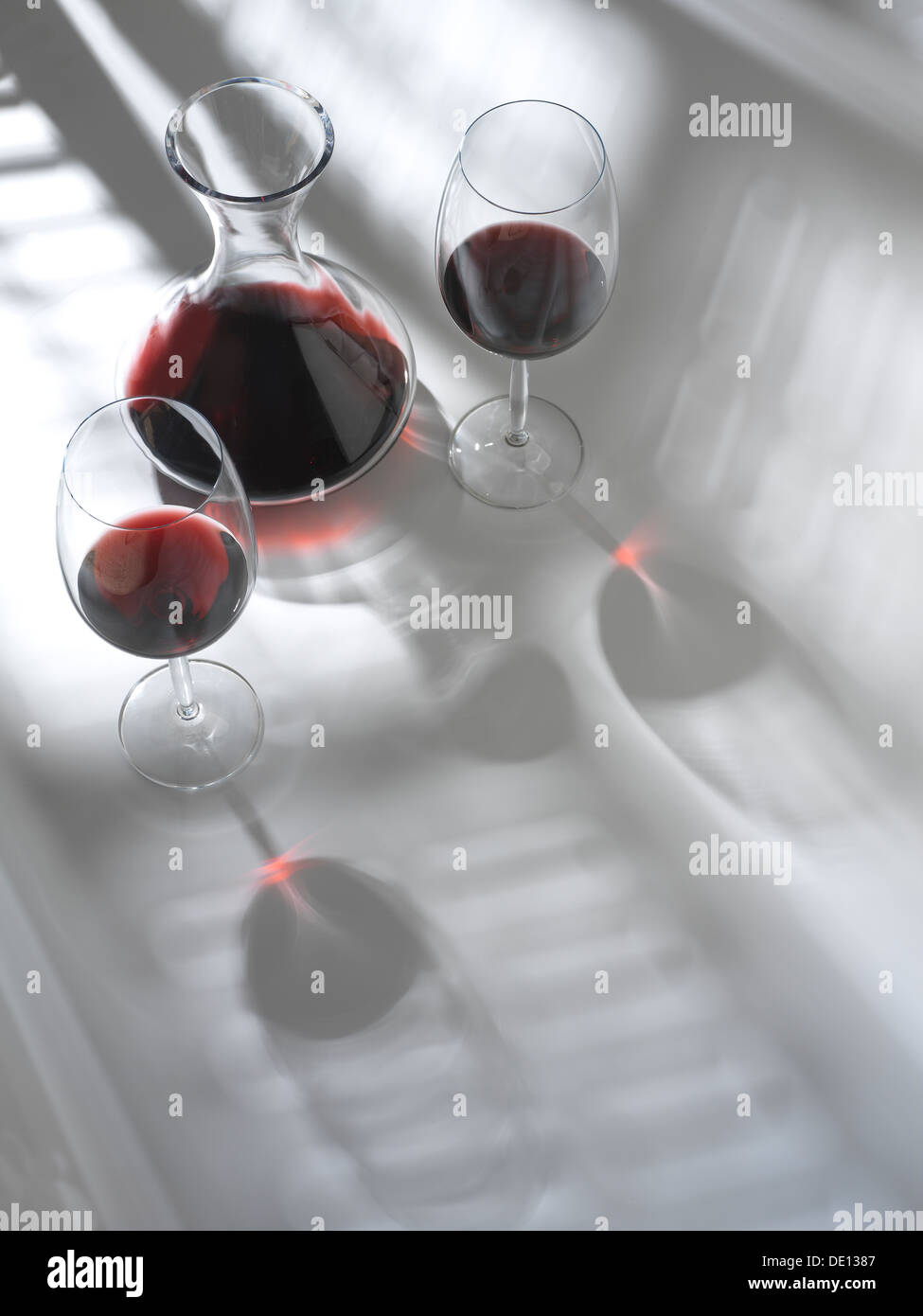 two red wine glasses and a decanter with the shadow of a window blind Stock Photo