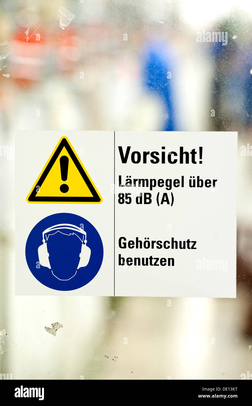 Sign in German, Caution noise levels above 85 dB, use hearing protection, company guidelines for use of hearing protection in Stock Photo