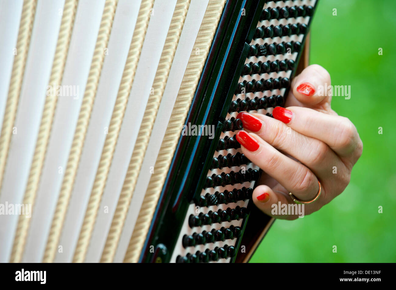 Hand of a female accordion player, red fingernails on the bass register Stock Photo