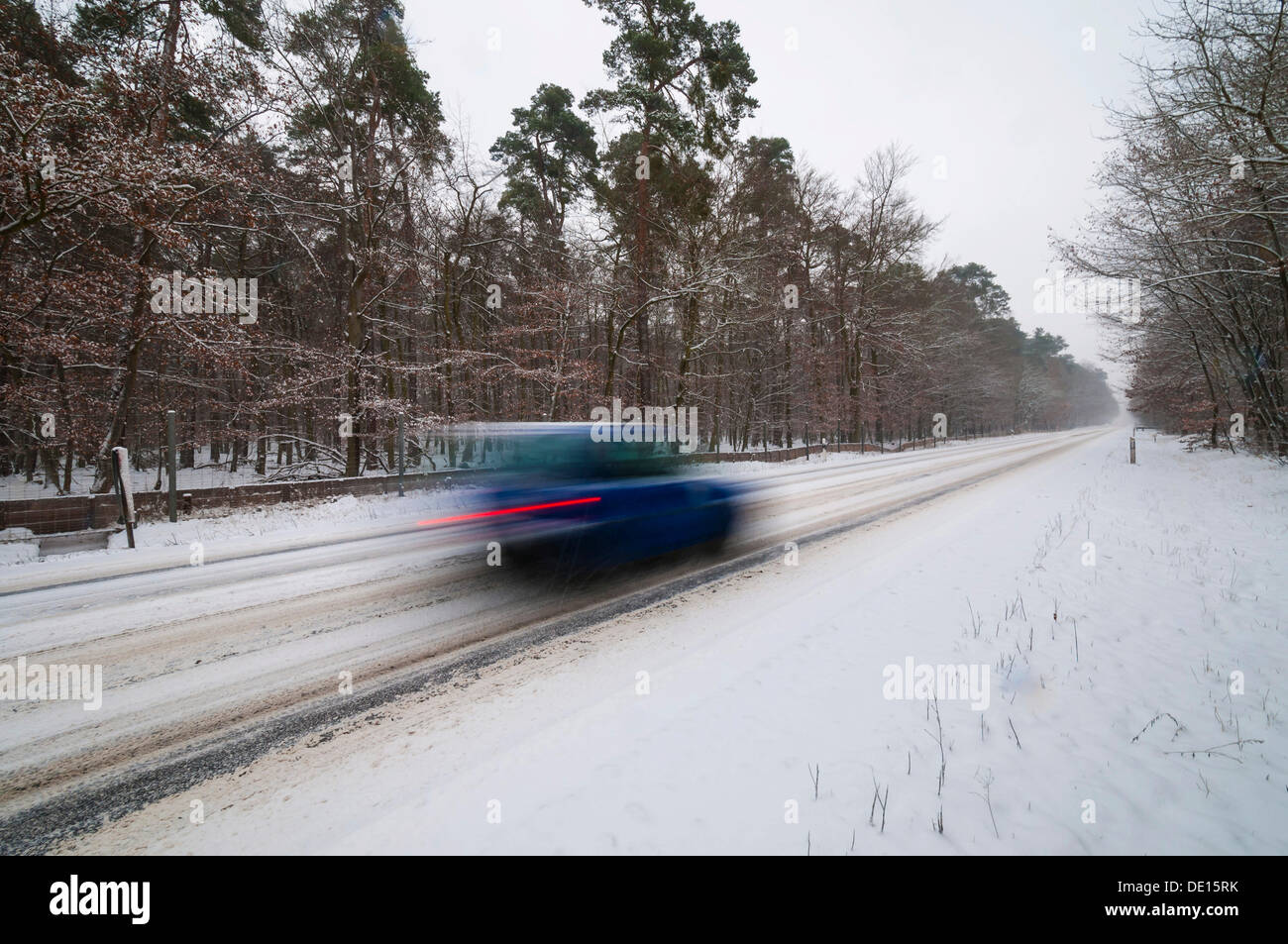 Snow-covered road in winter with car passing by quickly, Mörfelden, Hesse, Germany Stock Photo