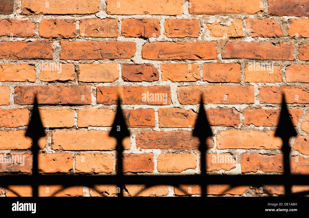 Red brick wall and black wrought iron fence Stock Photo