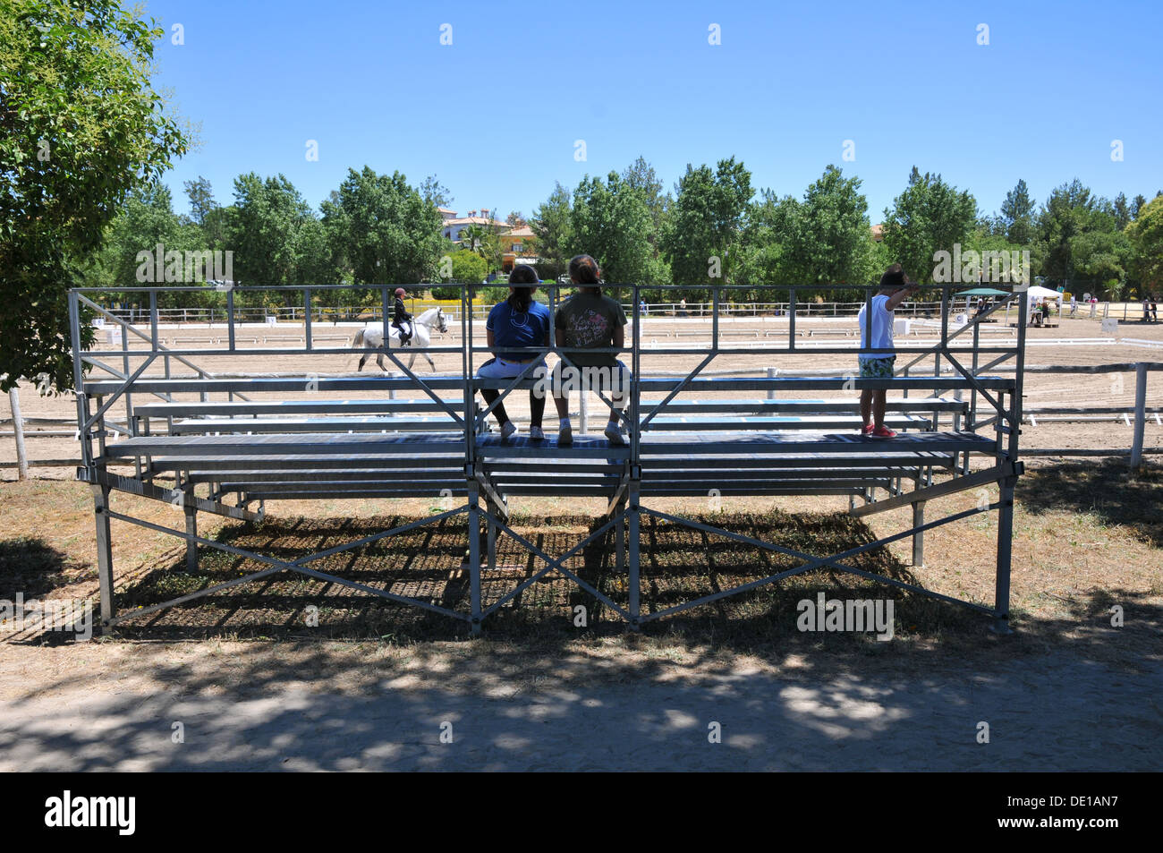 Back view of two people watching dressage event from iron stand. Stock Photo