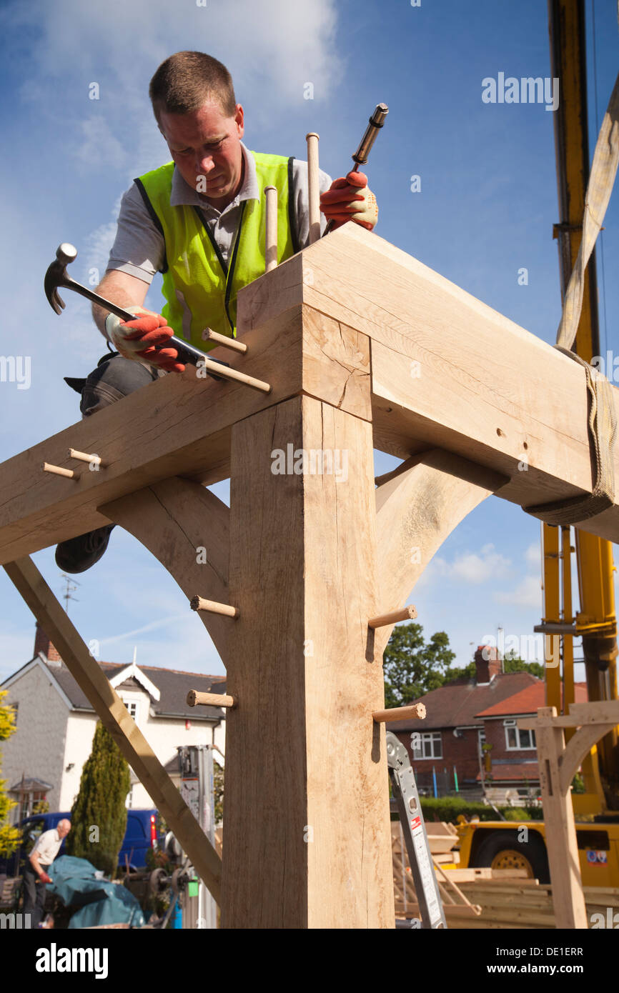 self building house, constructing green oak timber framed garage, pegging frame, whist crane lifts heavy structure Stock Photo