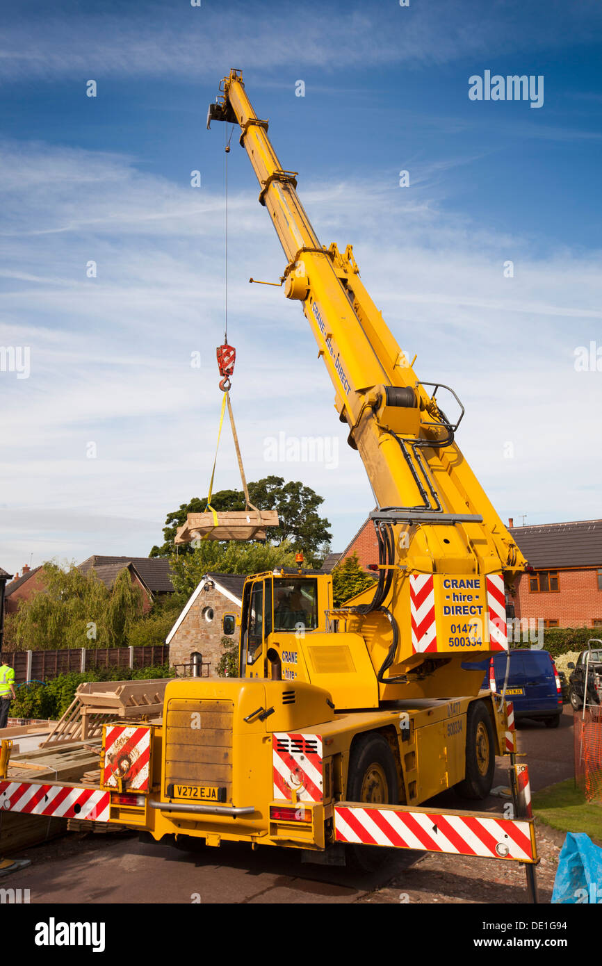 self building house, constructing green oak timber framed structure, using hired crane to lift heavy wooden components Stock Photo