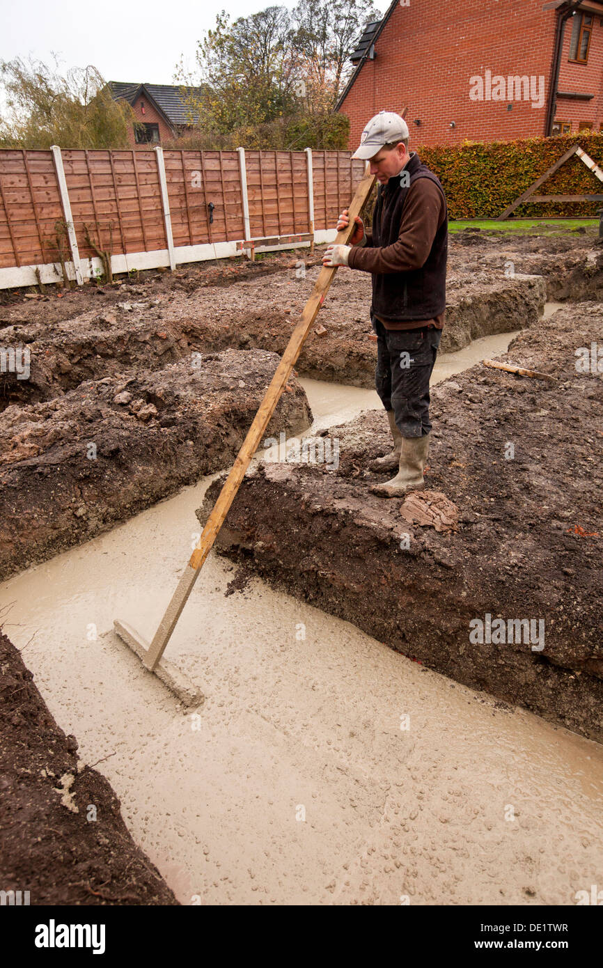 self building house, poured concrete foundations being tamped level by