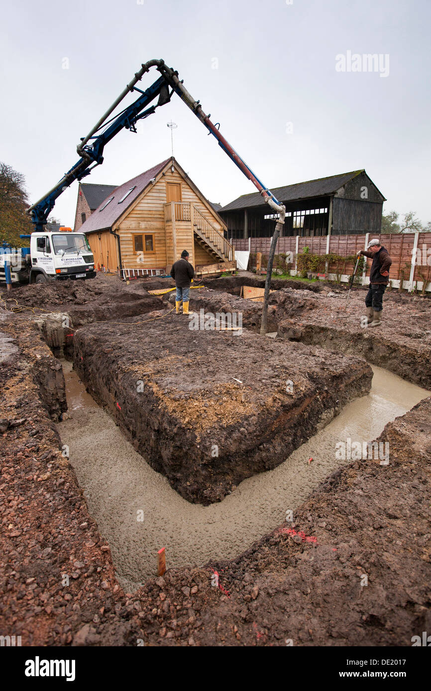 self building house, concrete foundations being poured and tamped level Stock Photo