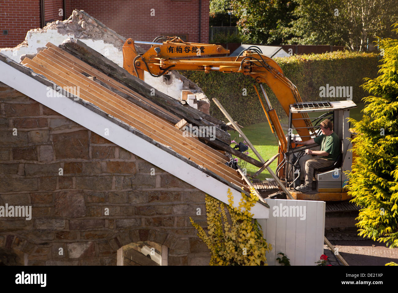 self building house, demolishing roof of old stone built outbuilding to clear site ready for building new house Stock Photo