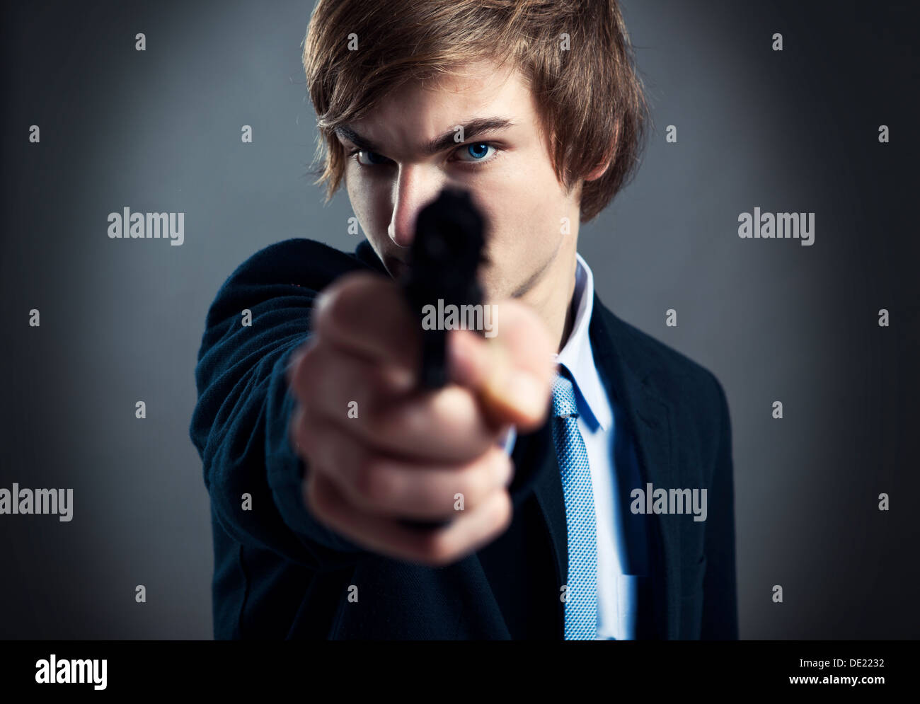 Stressed businessman holding and pointing a gun to the camera Stock Photo
