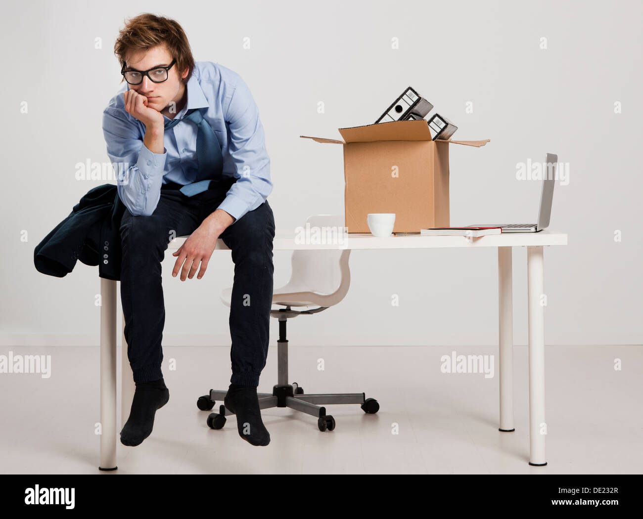 Young man sitting on the desk after being fired Stock Photo