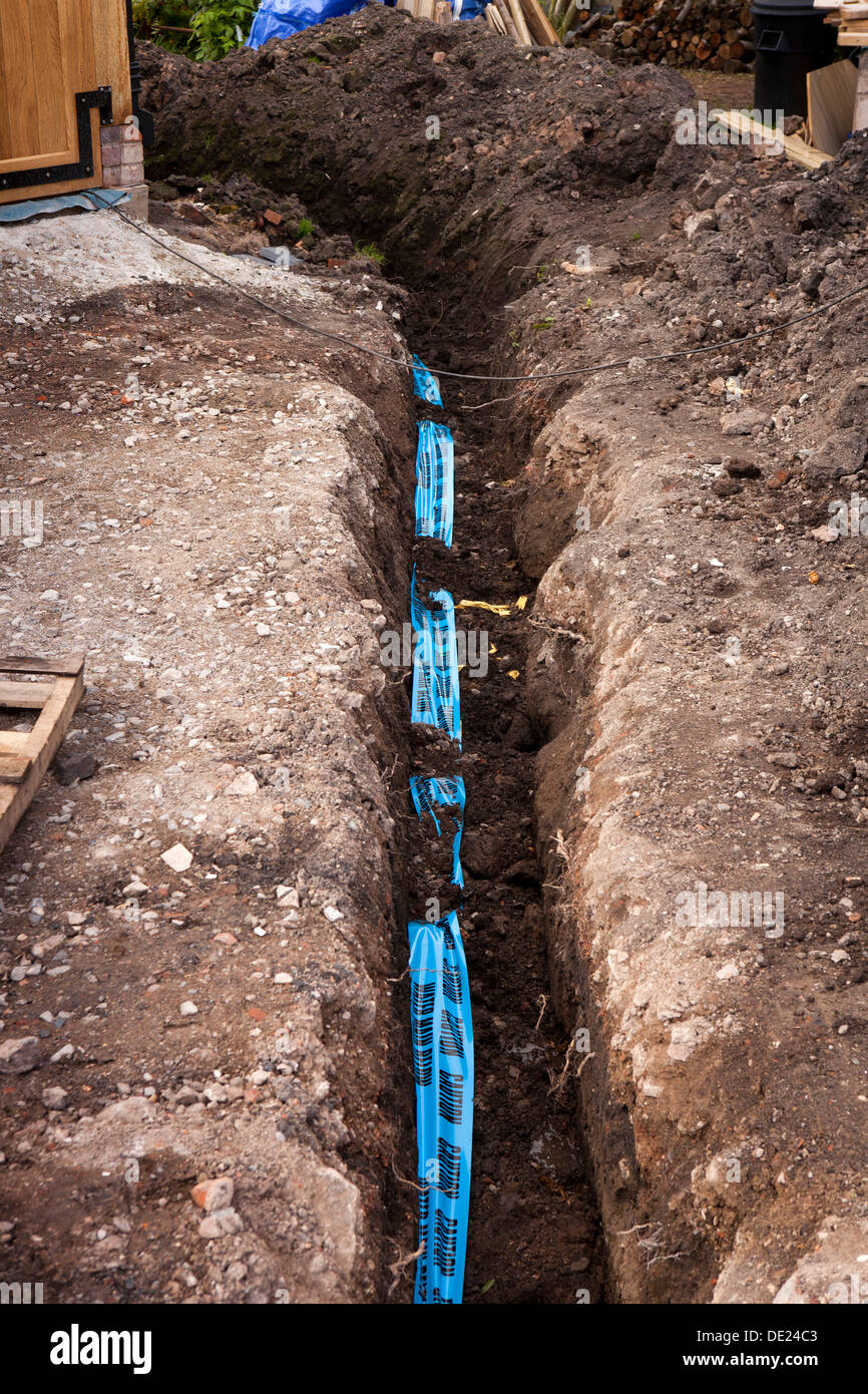 self building house, Blue Caution Water Main Below warning tape above buried water supply pipe Stock Photo