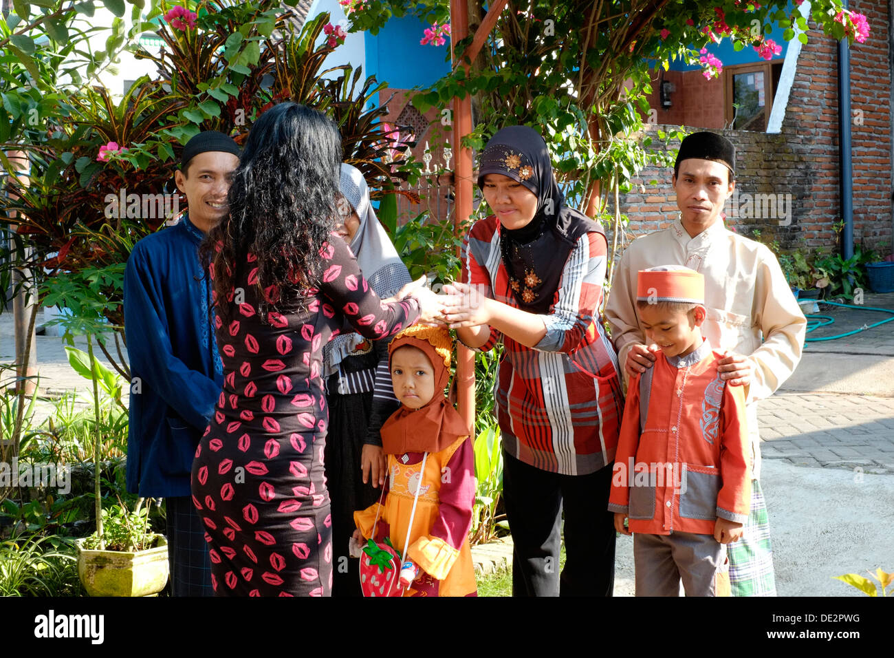 local woman greeting her neighbours who are visiting traditional during the idul fitri holidays Stock Photo