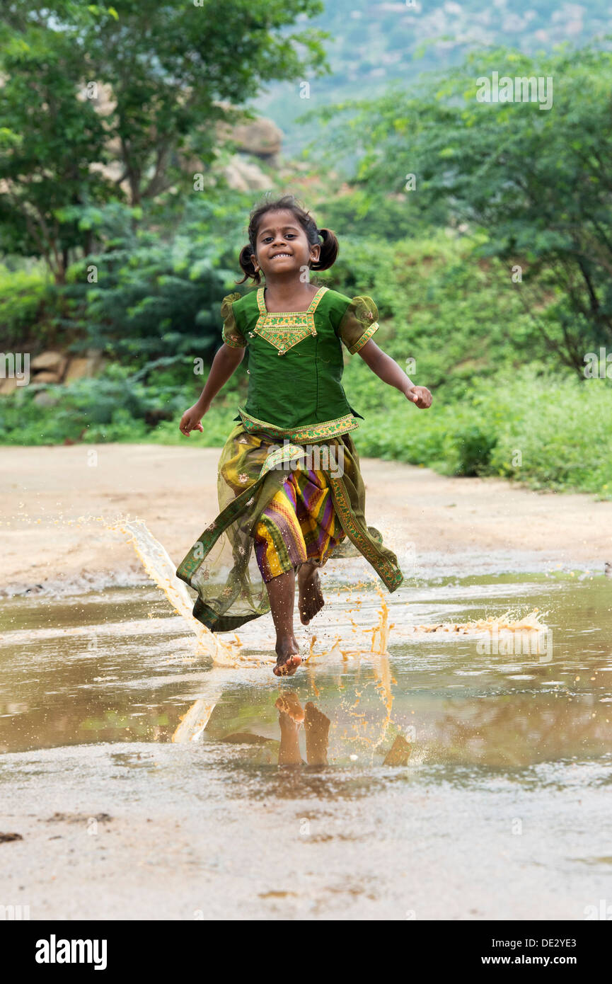 Rural Indian village girl running through a muddy puddle. Andhra Stock