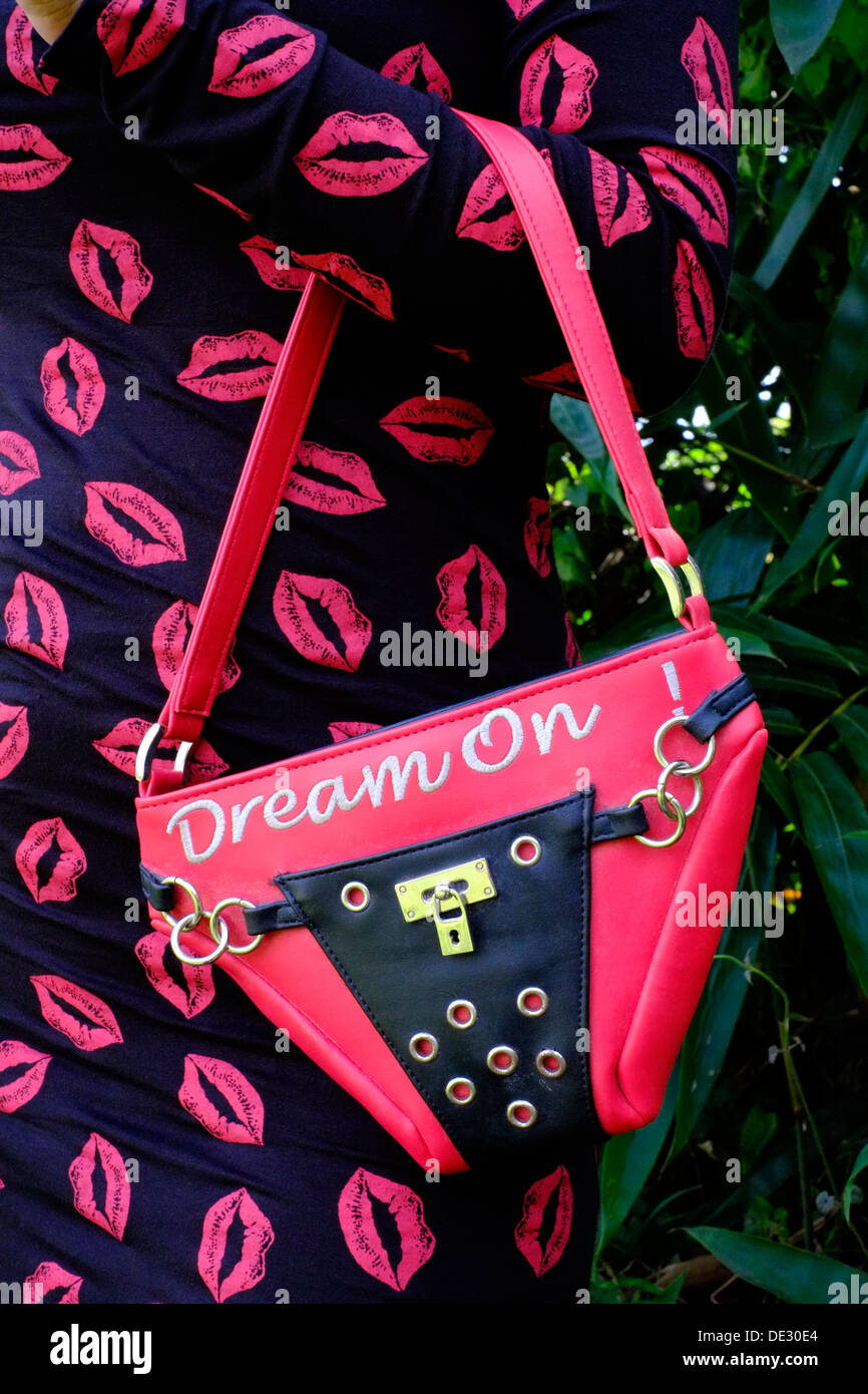 fashionable indonesian woman holding unusual handbag on her arm wearing lipstick kisses dress Stock Photo