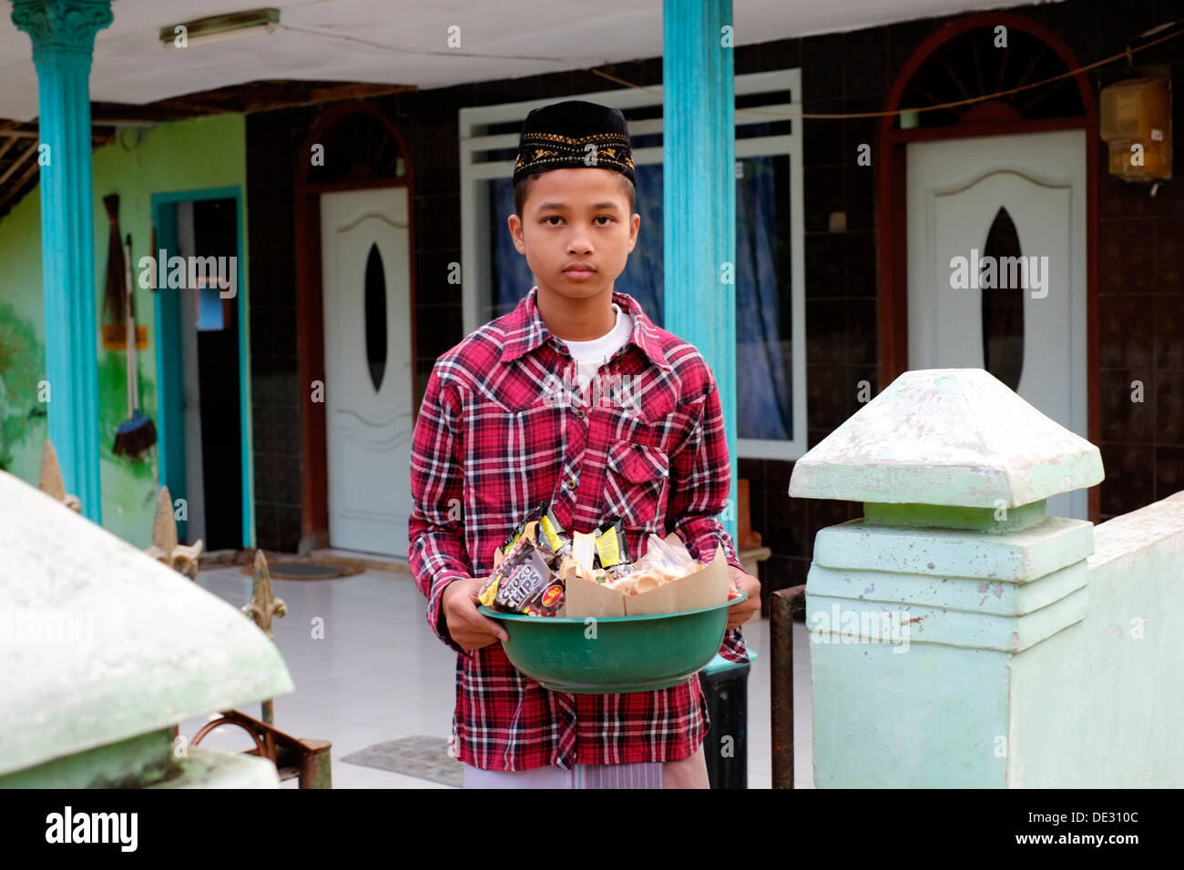 young indonesian boy with basket of snacks for traditional offering to the village mosque Stock Photo