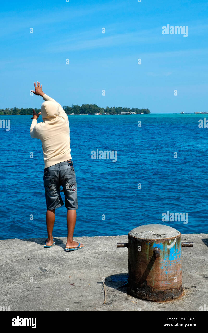 local resident male casts his fishing line into the sea off the pier on karimunjawa island java indonesia Stock Photo