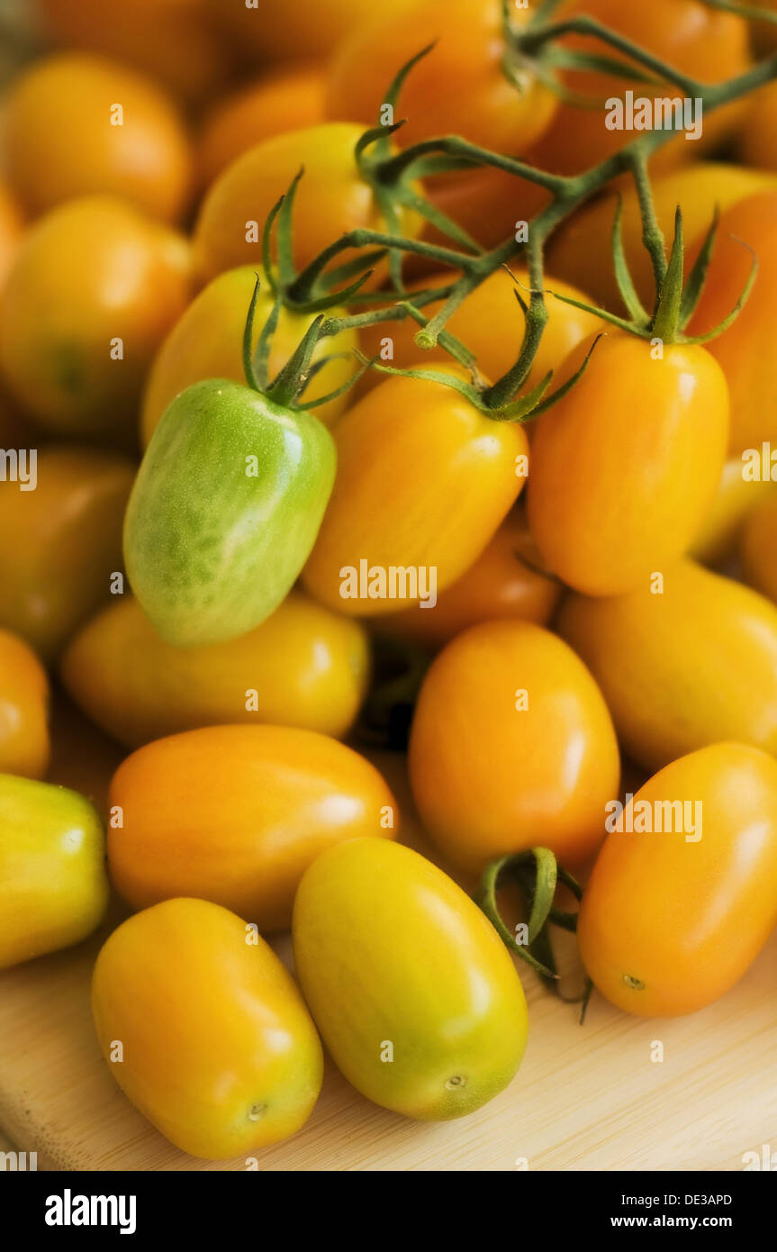 Orange Plum Tomatos on a Cutting Board, One Fruit is Green. Solanum lycopersicon Stock Photo
