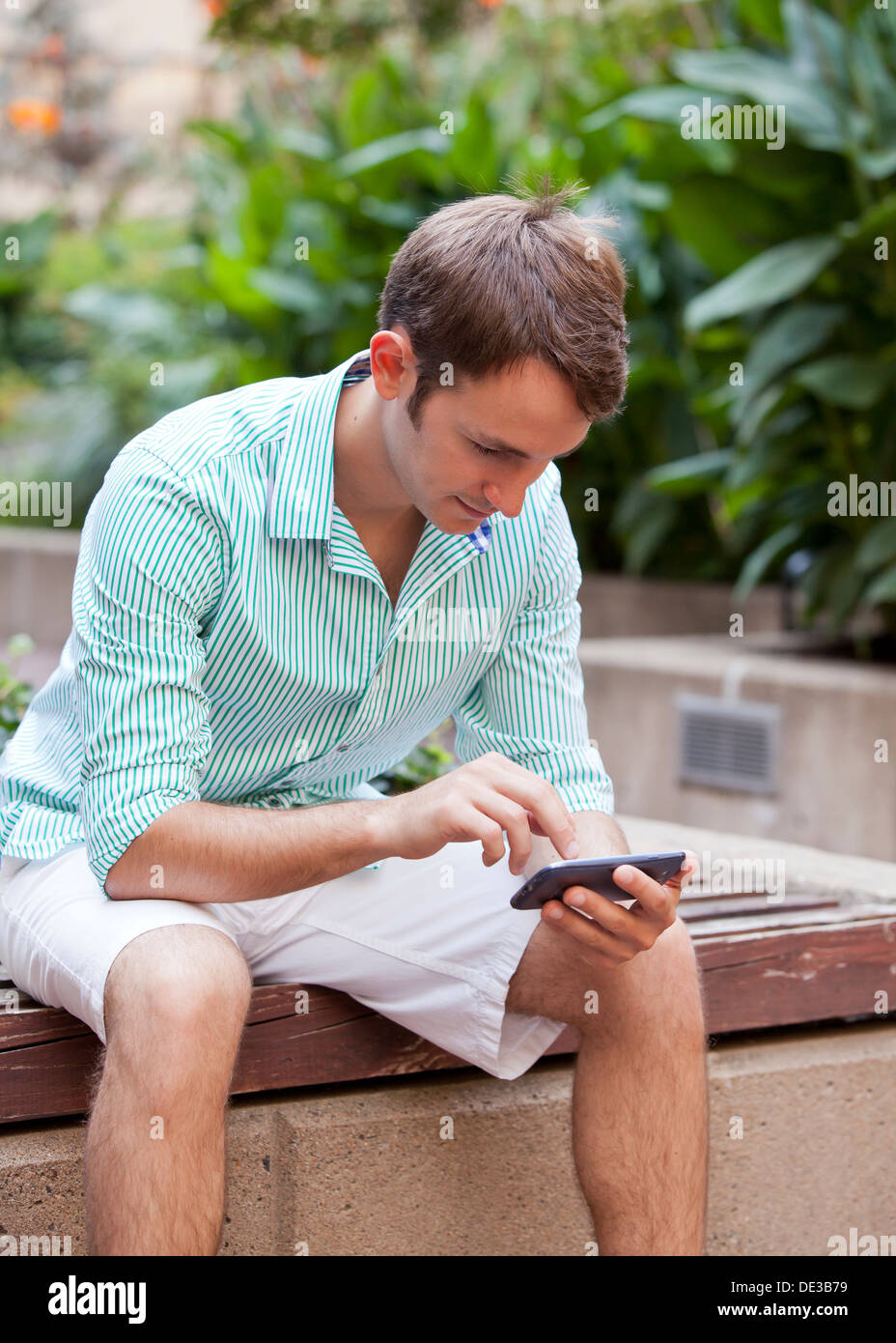 Man sitting in garden using a smart phone Stock Photo